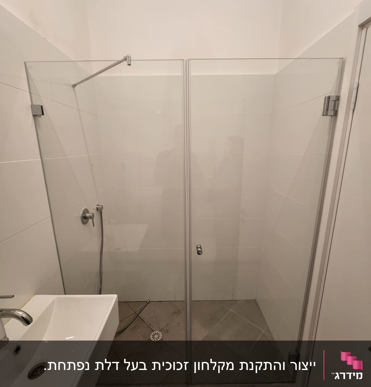 מקלחון זכוכית עם ראש מקלחת וקיר אריחים לבנים